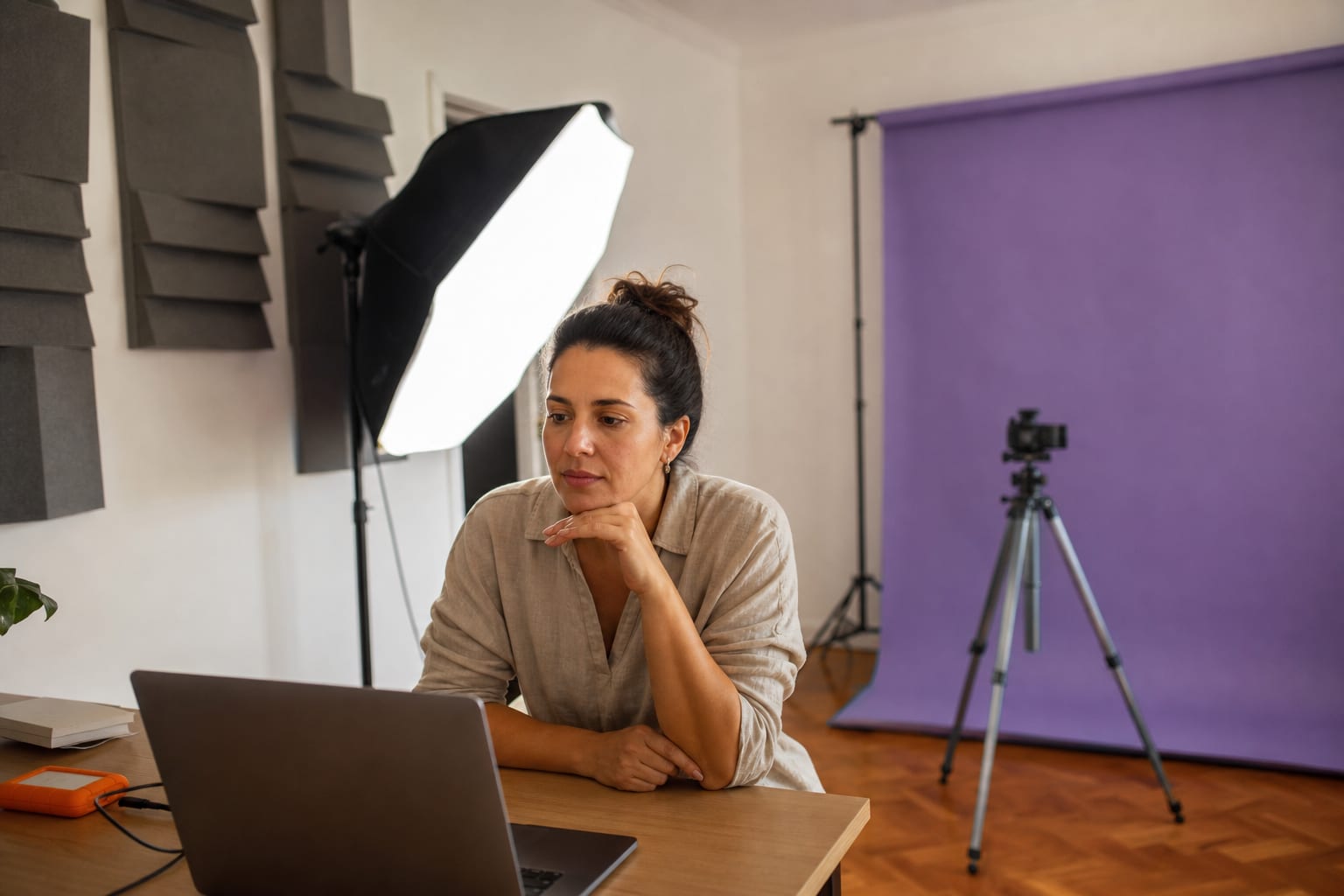 Produtora digital conferindo o painel de vendas no notebook dentro do estúdio montado em casa